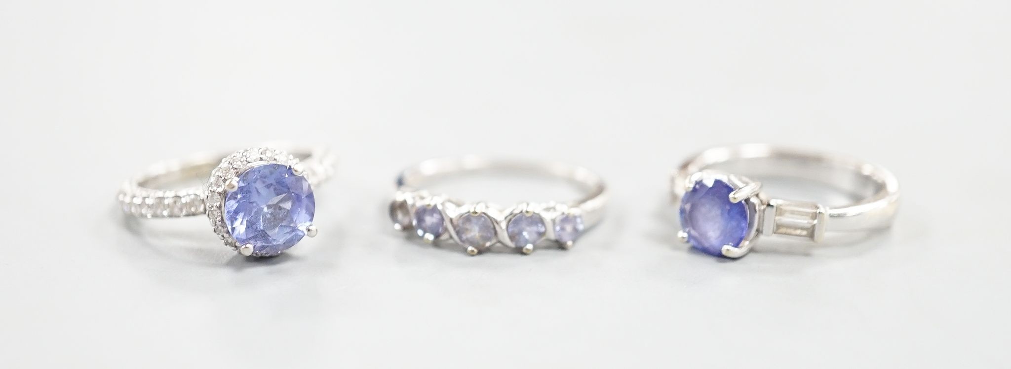 Two modern 18k white metal, tanzanite and diamond set dress rings, size J, gross 8.3 grams and a modern 9ct white gold and gem set ring, gross 2 grams.